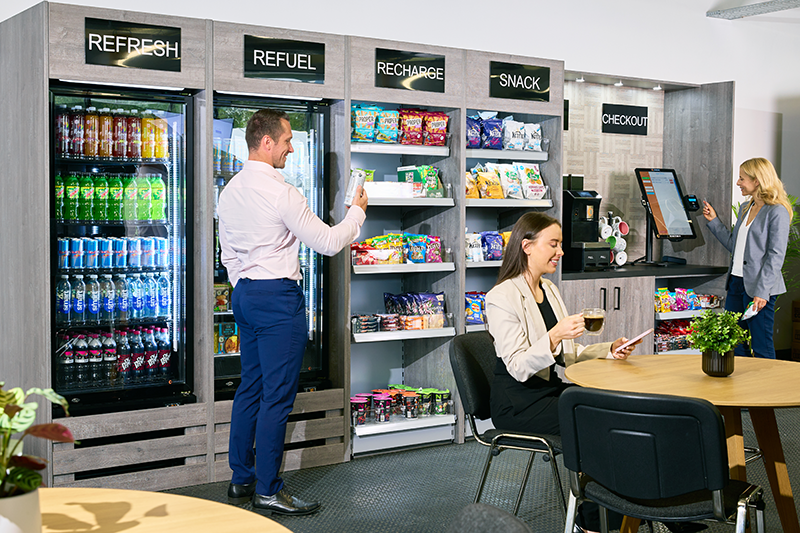 Employees gather around an office micro market snacking and perusing items.