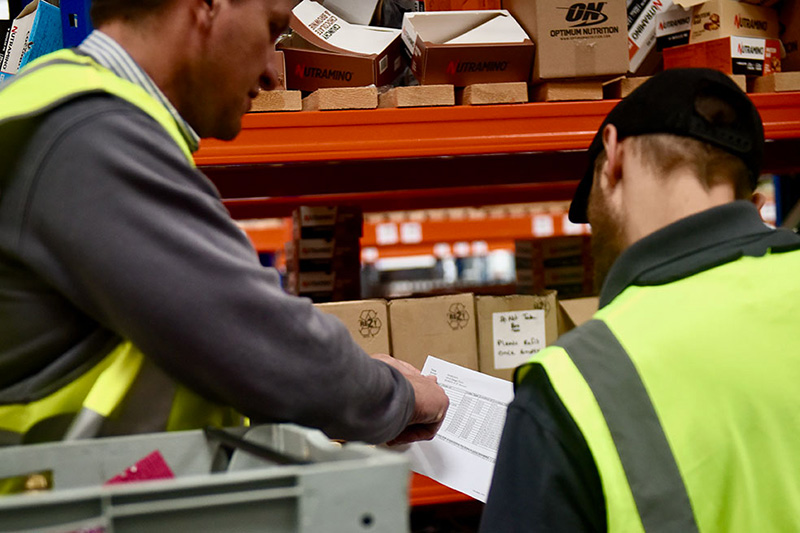 Two employees collaborate over a warehouse order.